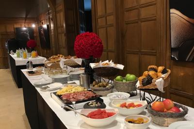 Chambre d'hôtel lumineuse avec lit double, bureau bleu, fauteuil, télévision et balcon offrant une vue sur l'extérieur.