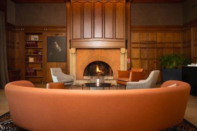 Chambre d'hôtel lumineuse avec lit double, bureau bleu, fauteuil, télévision et balcon offrant une vue sur l'extérieur.