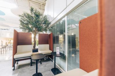 Salle de réunion moderne avec table blanche, chaises noires, mur bleu et éclairage intégré au plafond.