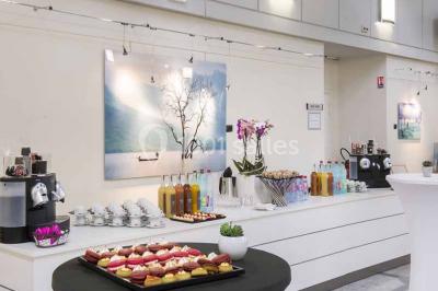 Salle de réunion moderne avec table blanche, chaises noires, mur bleu et éclairage intégré au plafond.