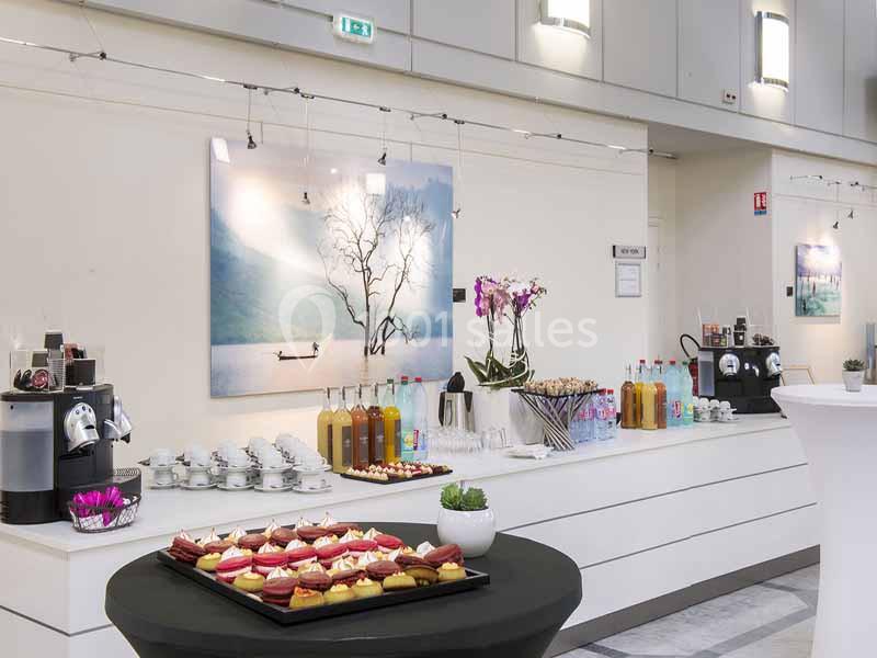 Table de buffet avec boissons, viennoiseries et desserts, dans une salle lumineuse avec décorations murales.