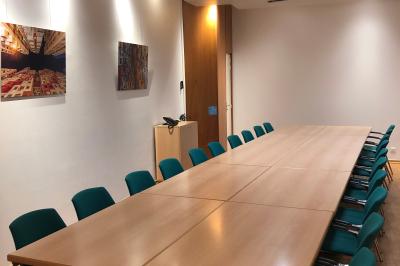 Salle de réunion moderne avec table blanche, chaises noires, mur bleu et éclairage intégré au plafond.