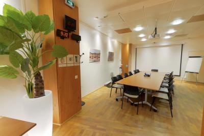 Salle de réunion moderne avec table blanche, chaises noires, mur bleu et éclairage intégré au plafond.