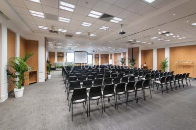 Salle de réunion moderne avec table blanche, chaises noires, mur bleu et éclairage intégré au plafond.