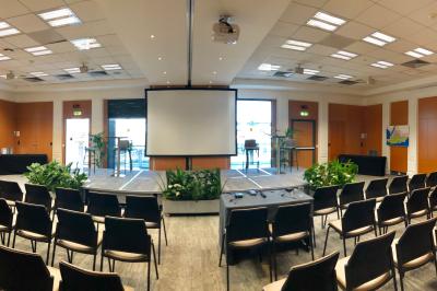 Salle de réunion moderne avec table blanche, chaises noires, mur bleu et éclairage intégré au plafond.