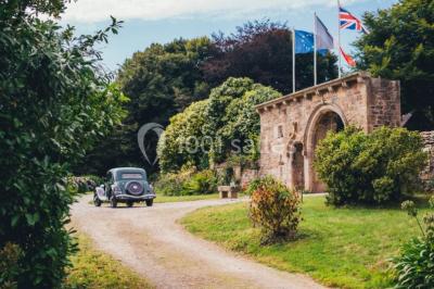 Salle de réception décorée avec des guirlandes lumineuses, remplie d'invités assis à des tables lors d'un événement.
