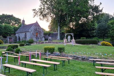 Salle de réception décorée avec des guirlandes lumineuses, remplie d'invités assis à des tables lors d'un événement.