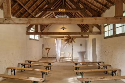 Salle de réception décorée avec des guirlandes lumineuses, remplie d'invités assis à des tables lors d'un événement.
