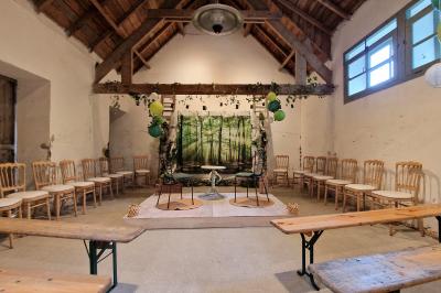 Salle de réception décorée avec des guirlandes lumineuses, remplie d'invités assis à des tables lors d'un événement.