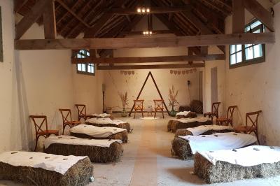 Salle de réception décorée avec des guirlandes lumineuses, remplie d'invités assis à des tables lors d'un événement.