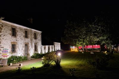 Salle de réception décorée avec des guirlandes lumineuses, remplie d'invités assis à des tables lors d'un événement.