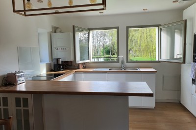 Chambre lumineuse avec un lit double, un mur bleu, une fenêtre avec rideaux jaunes et une porte en bois.