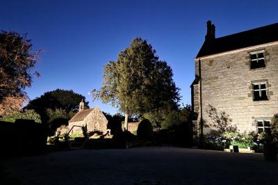Salle de réception décorée avec des guirlandes lumineuses, remplie d'invités assis à des tables lors d'un événement.