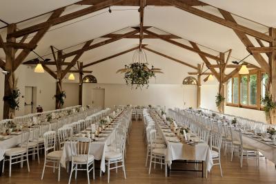Salle de réception décorée avec des guirlandes lumineuses, remplie d'invités assis à des tables lors d'un événement.