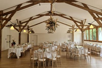 Salle de réception décorée avec des guirlandes lumineuses, remplie d'invités assis à des tables lors d'un événement.