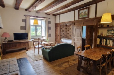 Chambre lumineuse avec un lit double, un mur bleu, une fenêtre avec rideaux jaunes et une porte en bois.