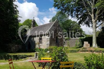 Salle de réception décorée avec des guirlandes lumineuses, remplie d'invités assis à des tables lors d'un événement.
