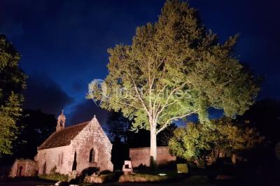 Salle de réception décorée avec des guirlandes lumineuses, remplie d'invités assis à des tables lors d'un événement.