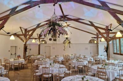 Salle de réception décorée avec des guirlandes lumineuses, remplie d'invités assis à des tables lors d'un événement.