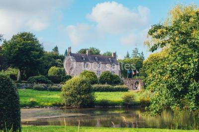 Salle de réception décorée avec des guirlandes lumineuses, remplie d'invités assis à des tables lors d'un événement.