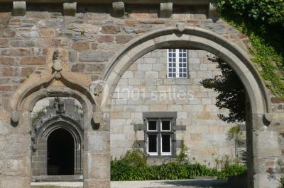 Salle de réception décorée avec des guirlandes lumineuses, remplie d'invités assis à des tables lors d'un événement.