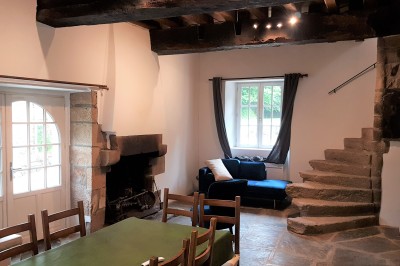 Chambre lumineuse avec un lit double, un mur bleu, une fenêtre avec rideaux jaunes et une porte en bois.