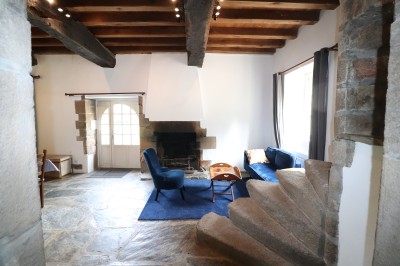 Chambre lumineuse avec un lit double, un mur bleu, une fenêtre avec rideaux jaunes et une porte en bois.