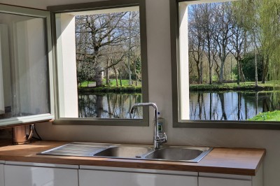 Chambre lumineuse avec un lit double, un mur bleu, une fenêtre avec rideaux jaunes et une porte en bois.