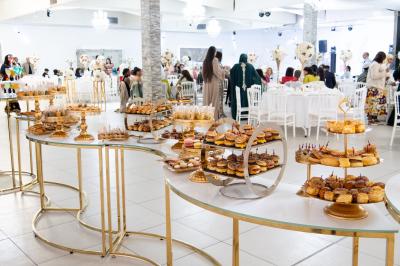 Buffet élégant avec une présentation variée de bouchées salées et sucrées sur des plateaux dorés en salle lumineuse.