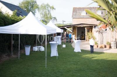 Voiture ancienne blanche décorée de fleurs blanches, stationnée sur un chemin près de vignes et d'un arbre.