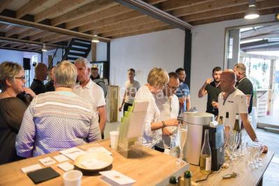 Voiture ancienne blanche décorée de fleurs blanches, stationnée sur un chemin près de vignes et d'un arbre.