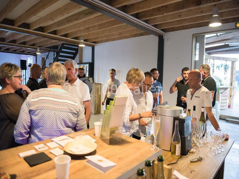 Groupe de personnes discutant autour d'un comptoir avec des boissons dans un espace intérieur lumineux.