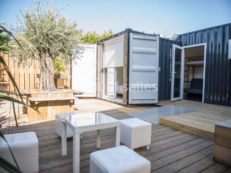 Terrasse en bois aménagée avec des meubles modernes, entourée de containers transformés en espaces habitables.