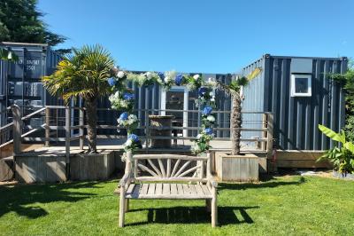 Voiture ancienne blanche décorée de fleurs blanches, stationnée sur un chemin près de vignes et d'un arbre.