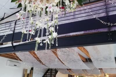 Voiture ancienne blanche décorée de fleurs blanches, stationnée sur un chemin près de vignes et d'un arbre.