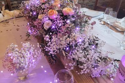 Voiture ancienne blanche décorée de fleurs blanches, stationnée sur un chemin près de vignes et d'un arbre.