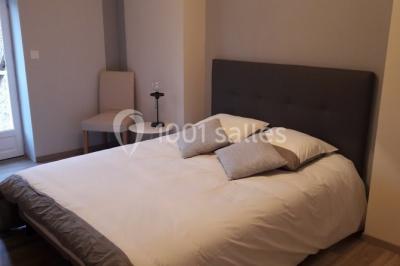 Chambre avec un lit double, tête de lit noire, tables de chevet, mur bleu et mobilier sombre sur un sol en parquet clair.