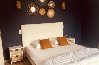 Tonneau en bois transformé en bar avec décoration végétale, verres et pancarte ’Servez-vous’ dans un jardin.