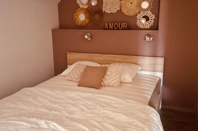 Tonneau en bois transformé en bar avec décoration végétale, verres et pancarte ’Servez-vous’ dans un jardin.