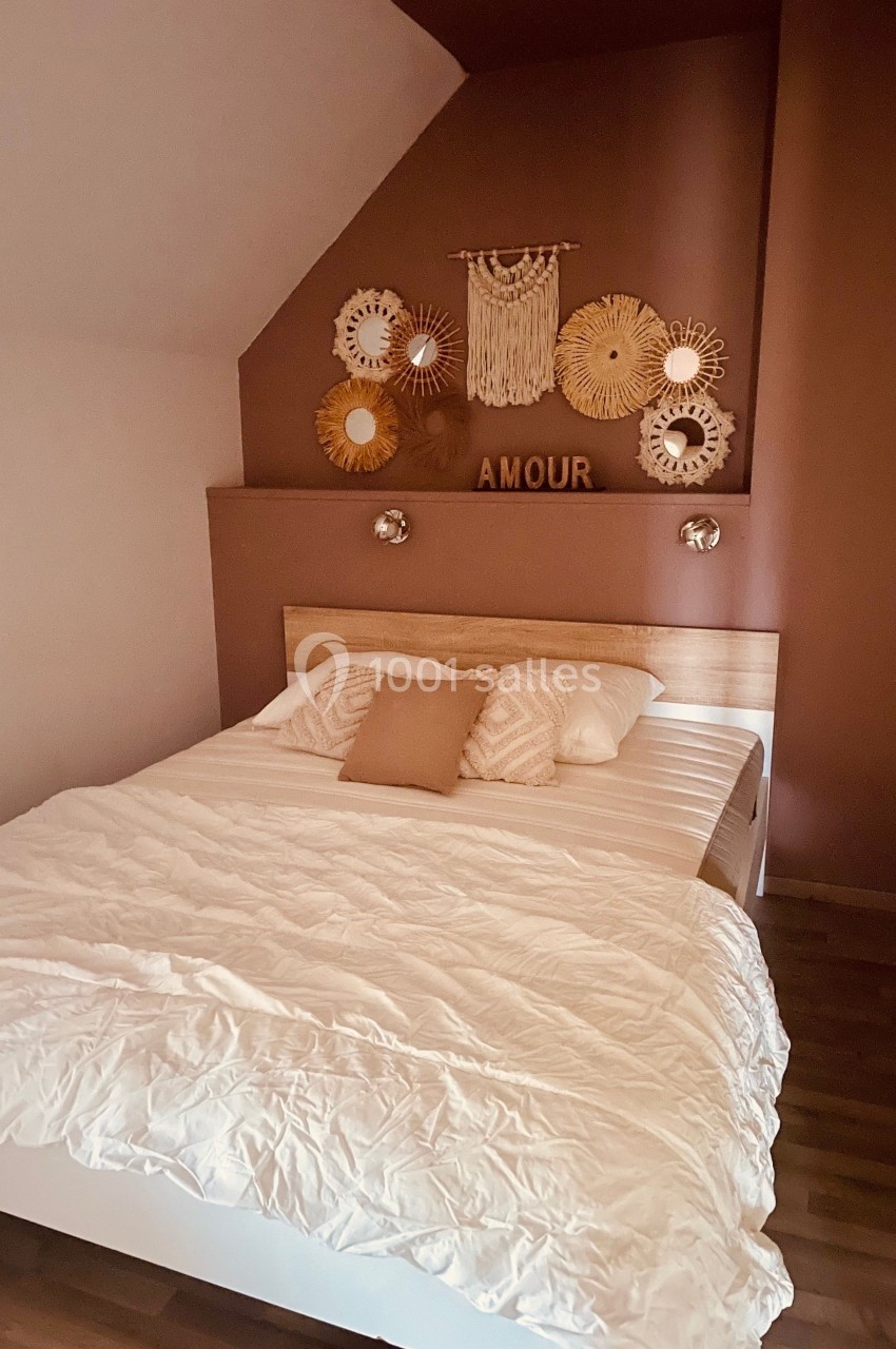 Chambre avec lit double, mur décoré de miroirs ronds et d'une suspension murale, ambiance chaleureuse et épurée.