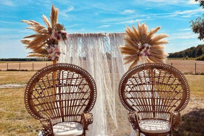 Tonneau en bois transformé en bar avec décoration végétale, verres et pancarte ’Servez-vous’ dans un jardin.