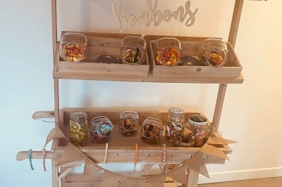 Tonneau en bois transformé en bar avec décoration végétale, verres et pancarte ’Servez-vous’ dans un jardin.