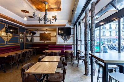 Terrasse d'une brasserie parisienne avec des tables et chaises colorées, située à l'angle d'une rue calme.