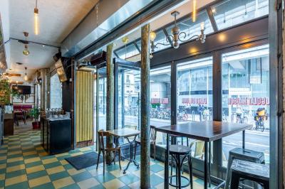 Terrasse d'une brasserie parisienne avec des tables et chaises colorées, située à l'angle d'une rue calme.