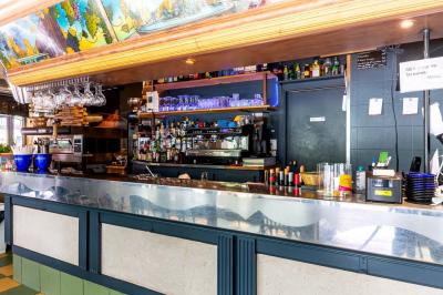 Terrasse d'une brasserie parisienne avec des tables et chaises colorées, située à l'angle d'une rue calme.