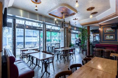 Terrasse d'une brasserie parisienne avec des tables et chaises colorées, située à l'angle d'une rue calme.