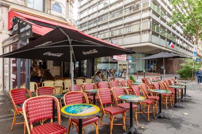 Terrasse d'une brasserie parisienne avec des tables et chaises colorées, située à l'angle d'une rue calme.