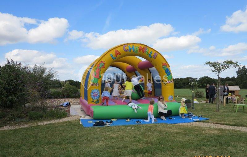 Des enfants jouent sur un château gonflable coloré dans un jardin par une journée ensoleillée.