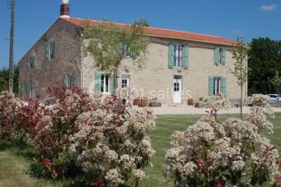 Chambre avec lits superposés en bois, parquet, papier peint floral, accès à une salle de bain et vue sur un jardin.