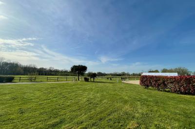 Chambre avec lits superposés en bois, parquet, papier peint floral, accès à une salle de bain et vue sur un jardin.